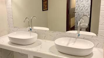 Un baño con dos lavamanos blancos, un espejo y una pared con azulejos.