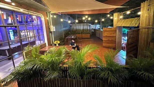 An indoor space with a wooden floor, a seating area with a table and chairs, and a large window with a view. - You empire Hostel and Bar (Pakse)
