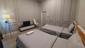 A hotel room with two beds, a TV, a desk, and a chair. - You empire Hostel and Bar (Pakse)