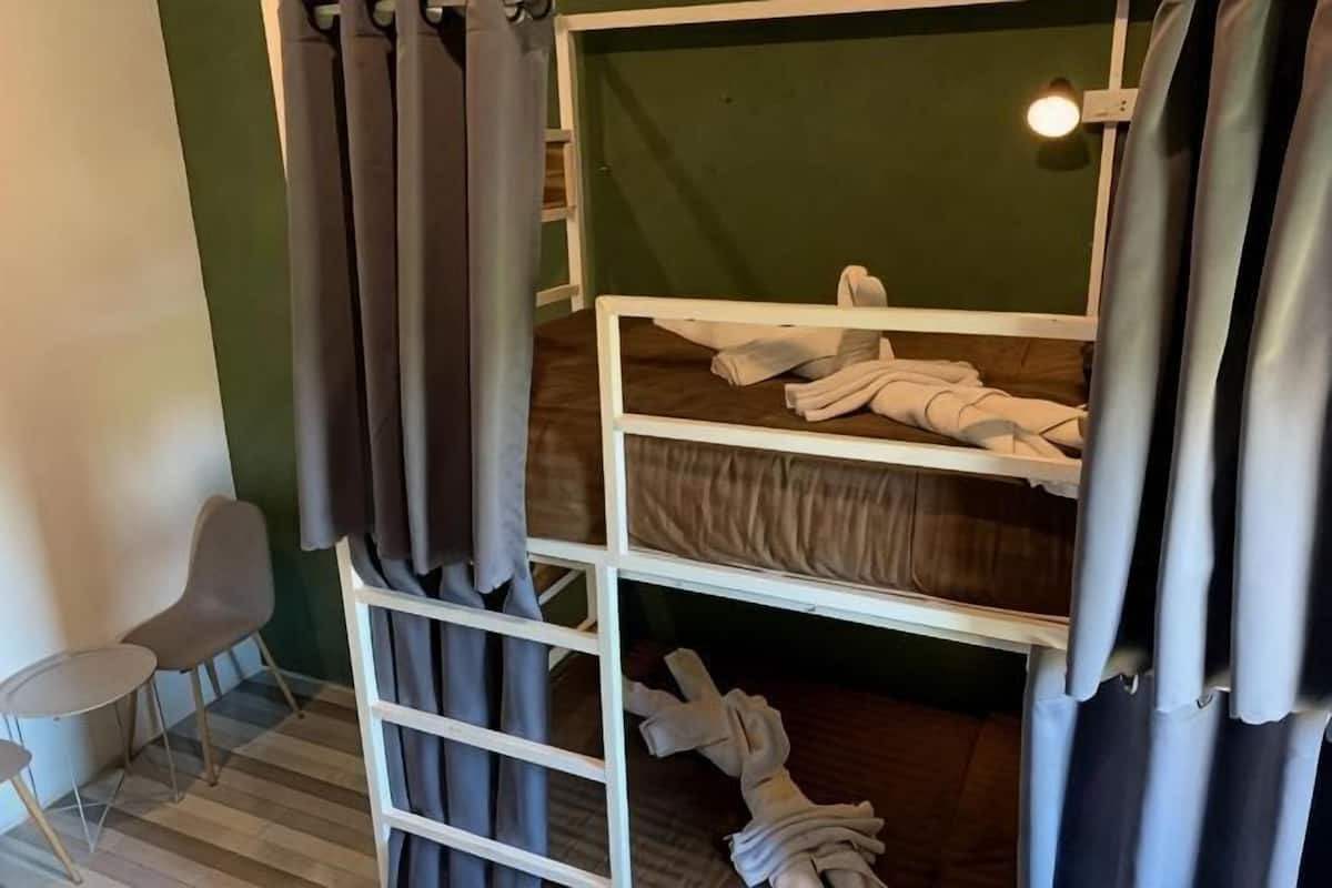 A bunk bed with towels, a chair, and a wall-mounted light fixture.