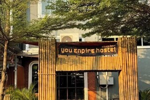 A hostel entrance with a bamboo archway and a sign that reads 'You Empire Hostel.'