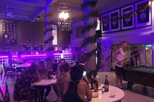 A bar area with pool tables, seating, and a DJ booth.