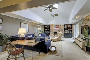 Un salon spacieux doté d’un ventilateur de plafond, d’une cheminée et d’une bibliothèque.