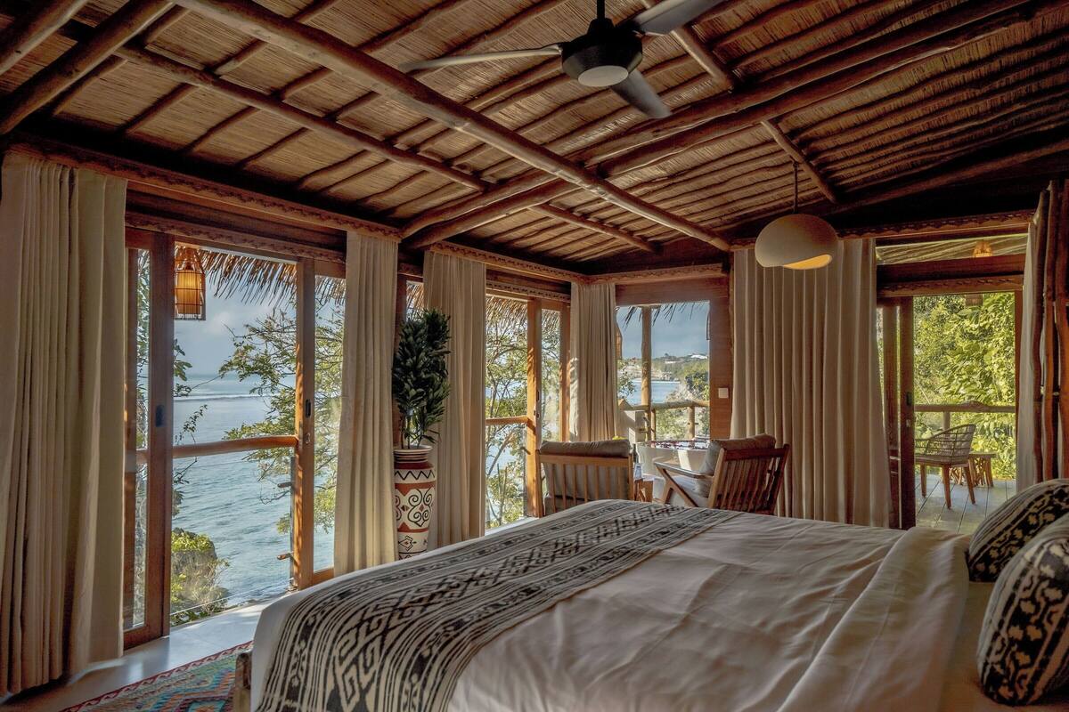 Un dormitorio con una cama grande, ventilador de techo y vista al mar.