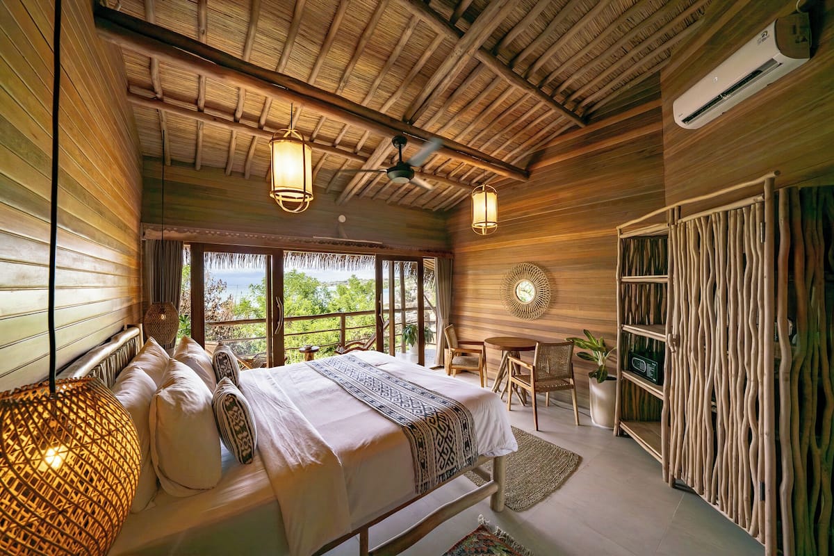 Un dormitorio espacioso con una cama grande, una zona de comedor y vistas al exterior.