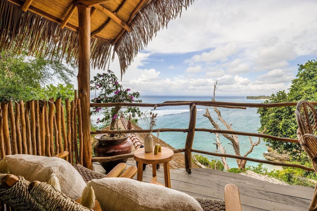 Una terraza de madera con techo de paja, con vista al mar.