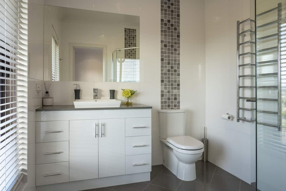 A modern bathroom with a white vanity, a toilet, and a glass shower enclosure.