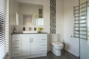 A modern bathroom with a white vanity, a toilet, and a glass shower enclosure.
