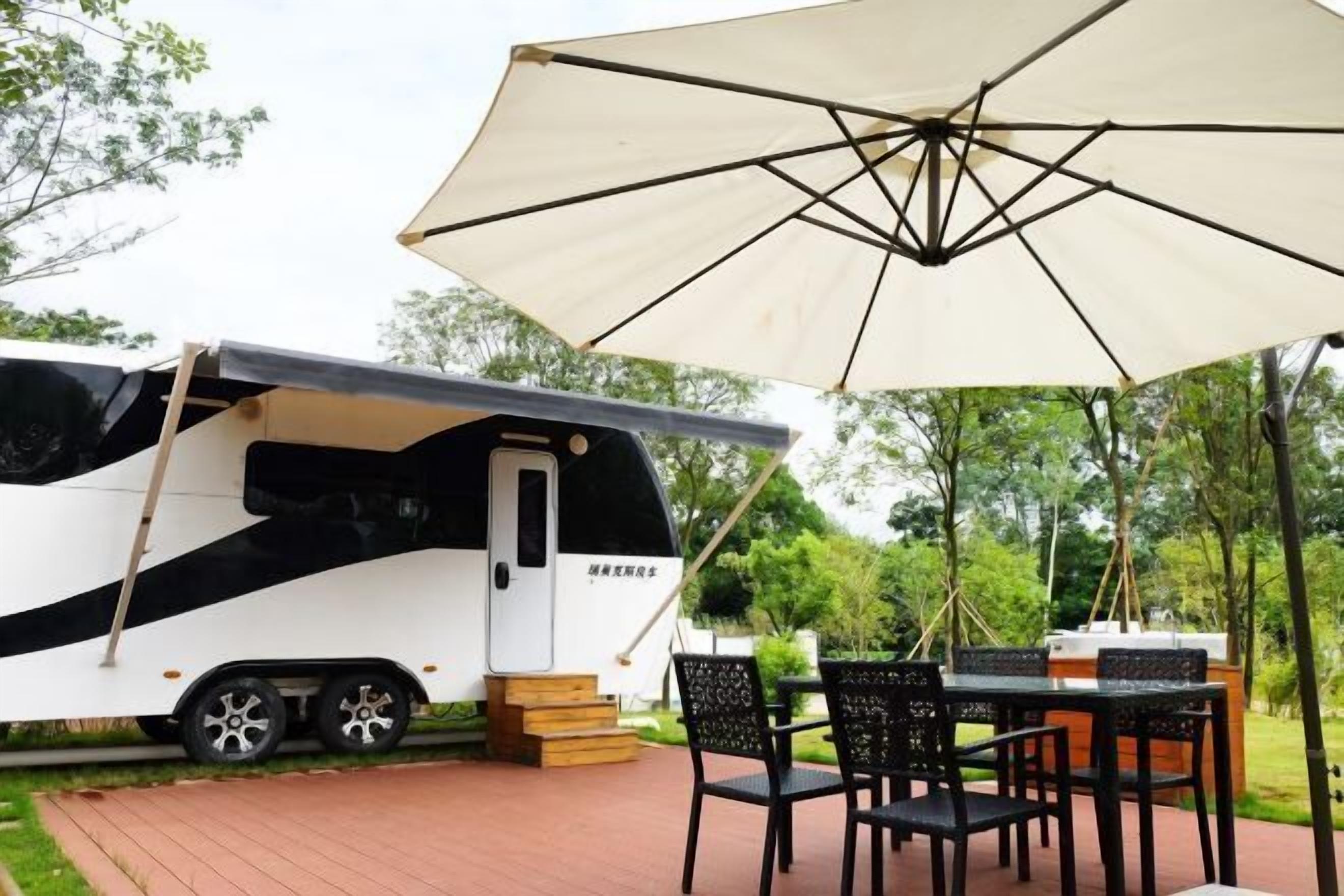 Ein Wohnmobil mit überdachter Sitzgruppe, einem Tisch und Stühlen.