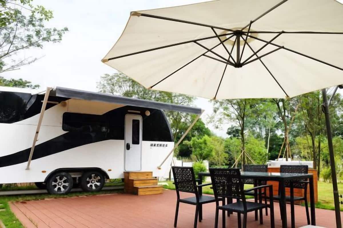 A recreational vehicle with a covered outdoor seating area, a table, and chairs.