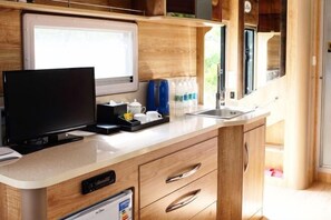 Cocina compacta con televisión integrada, pileta y muebles de madera.