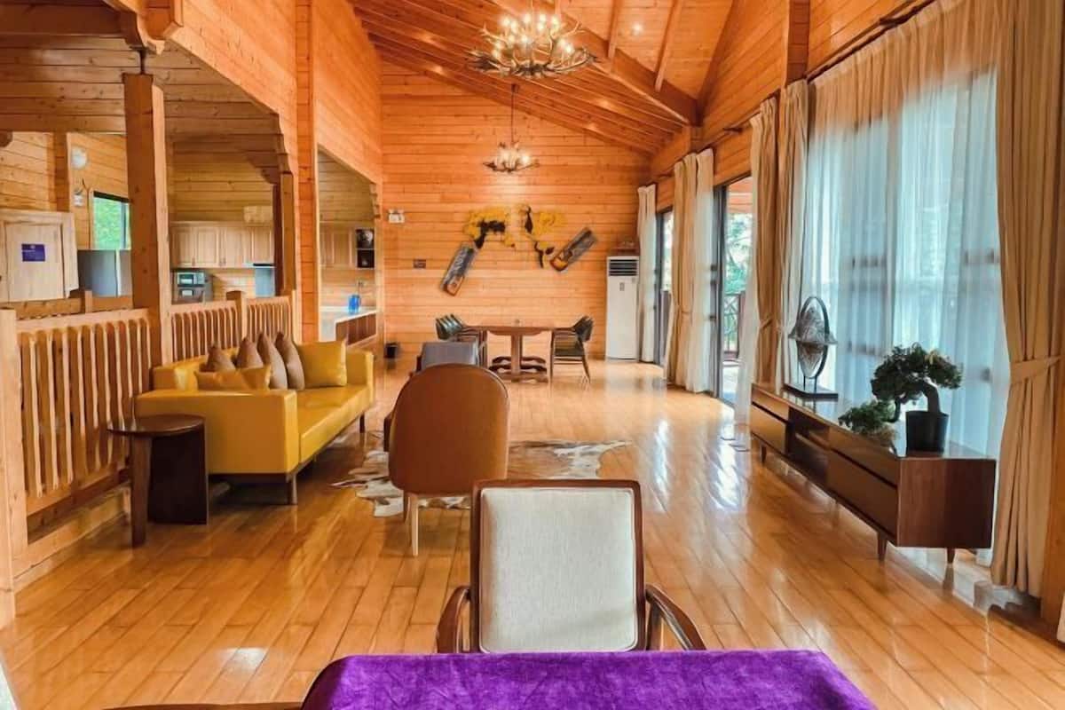 Un interior de madera con un sofá, sillas, una mesa de comedor y una araña.