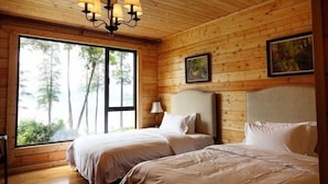 Een houten kamer met twee bedden, een groot raam en een kroonluchter.