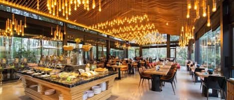 Un restaurant doté d’un buffet central, d’un plafond en bois et de grandes fenêtres.