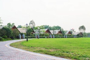A pathway leading to a row of cottages with a grassy lawn in the foreground. - Midea Egret Lake Car Theme Hotel (Foshan)