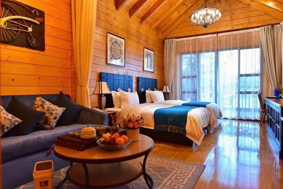 Interior de madera con una cama, un sofá y una mesa redonda con frutas.