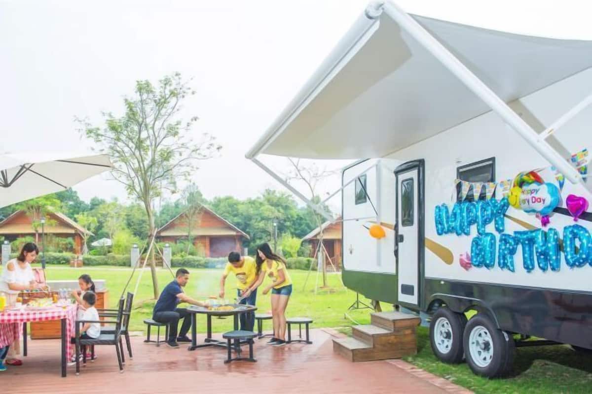 Una fiesta de cumpleaños con una carpa y un remolque decorado con adornos de 'Happy Birthday'.