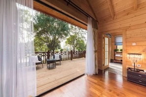A wooden interior with a large window, a wooden deck outside, and a view of trees. - Midea Egret Lake Car Theme Hotel (Foshan)