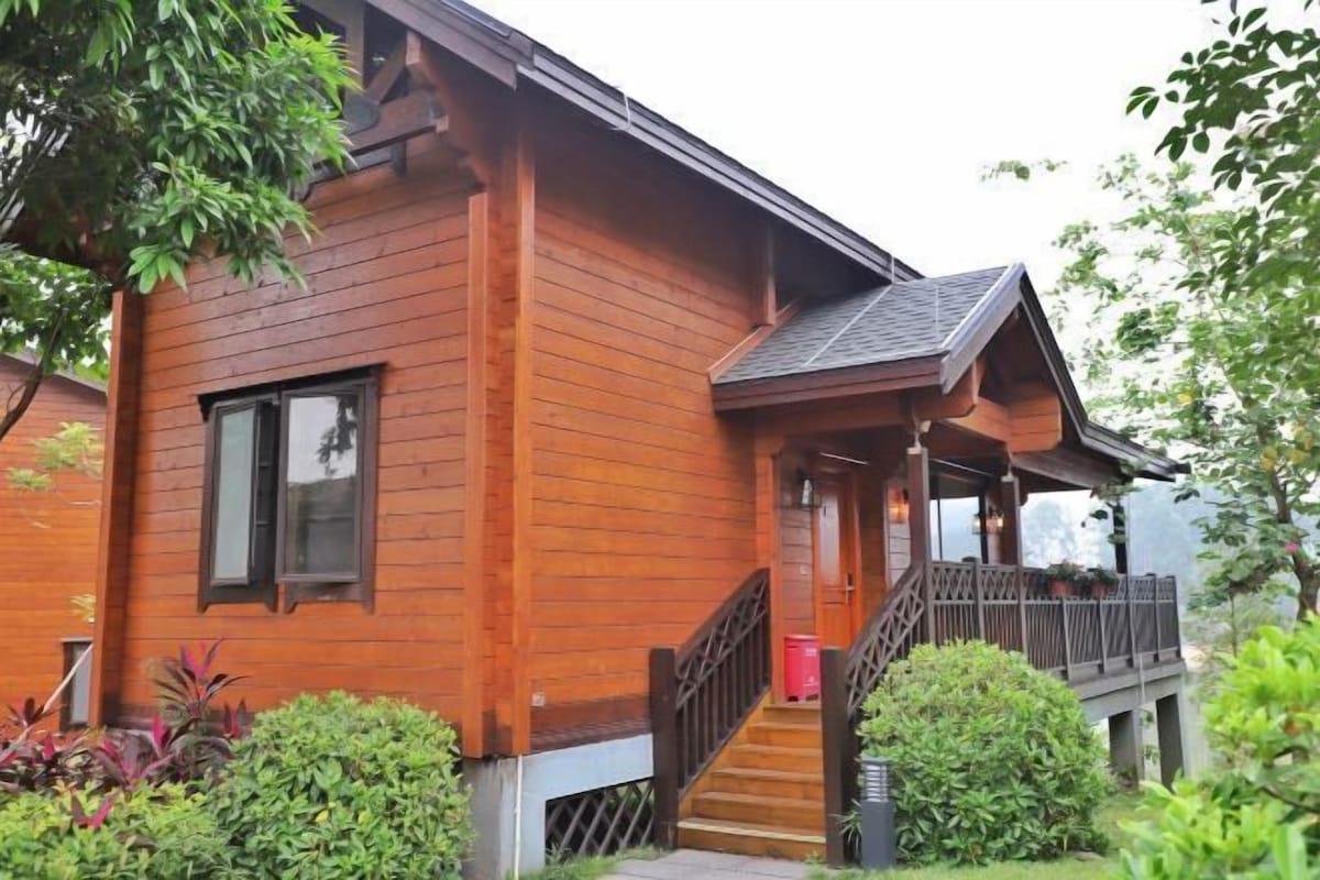 A wooden house with a porch, a staircase, and a small garden area.