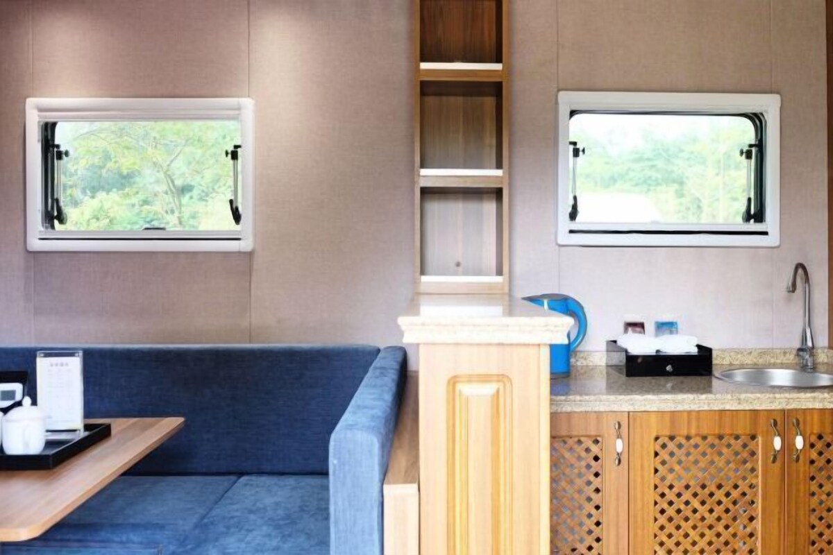 A compact kitchenette with two windows, a sink, and a countertop.