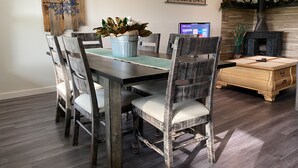 Un comedor con una mesa de madera, sillas y un ordenador portátil sobre la mesa.