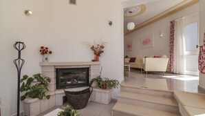 Ein modernes Wohnzimmer mit Kamin, einer Treppe zu einer anderen Ebene und einem Essbereich im Hintergrund.