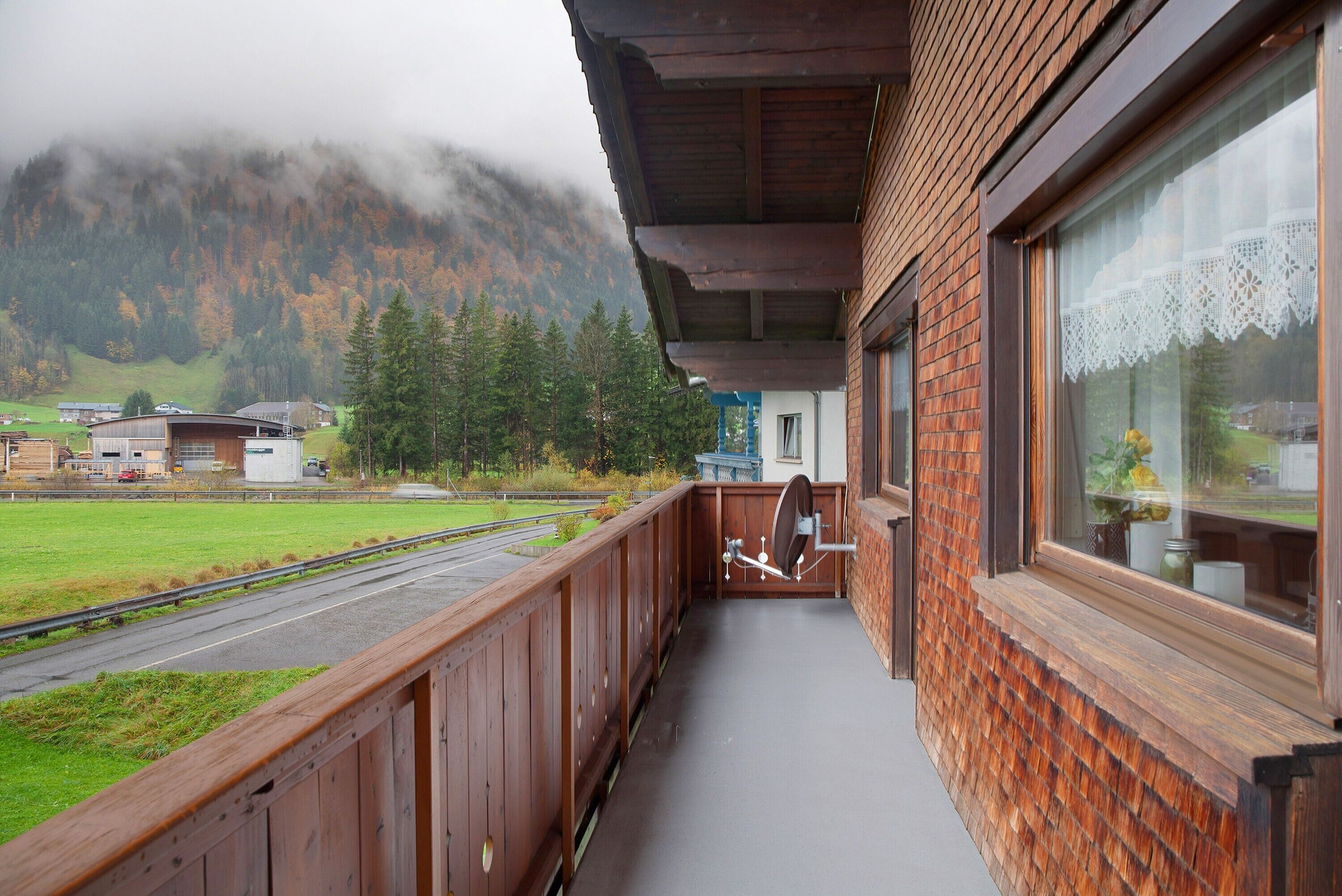 Un balcon avec vue sur une montagne et une route.
