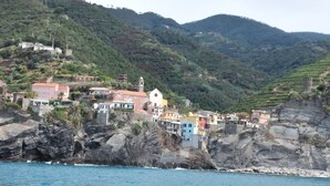 Un village côtier dont les bâtiments sont adossés à de hautes falaises rocheuses surplombant la mer.