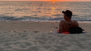 A beach with a sunset, waves, and a person sitting on the sand. - A/C WIFI Zona Romantica Private Balcony Roof Top/Pool 5 Blocks from the beach (Puerto Vallarta)