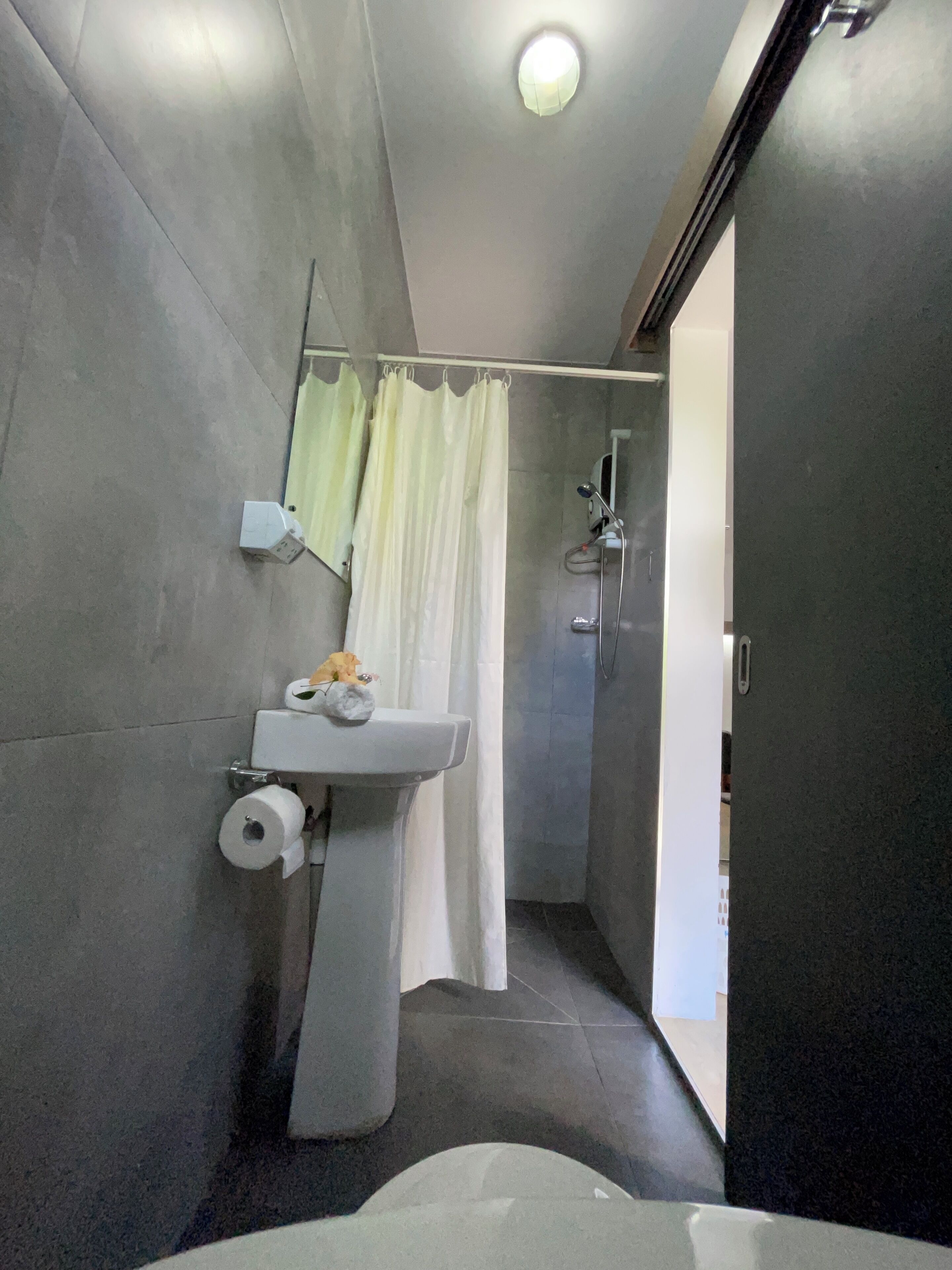 A modern bathroom with a toilet, a shower, and a sink.