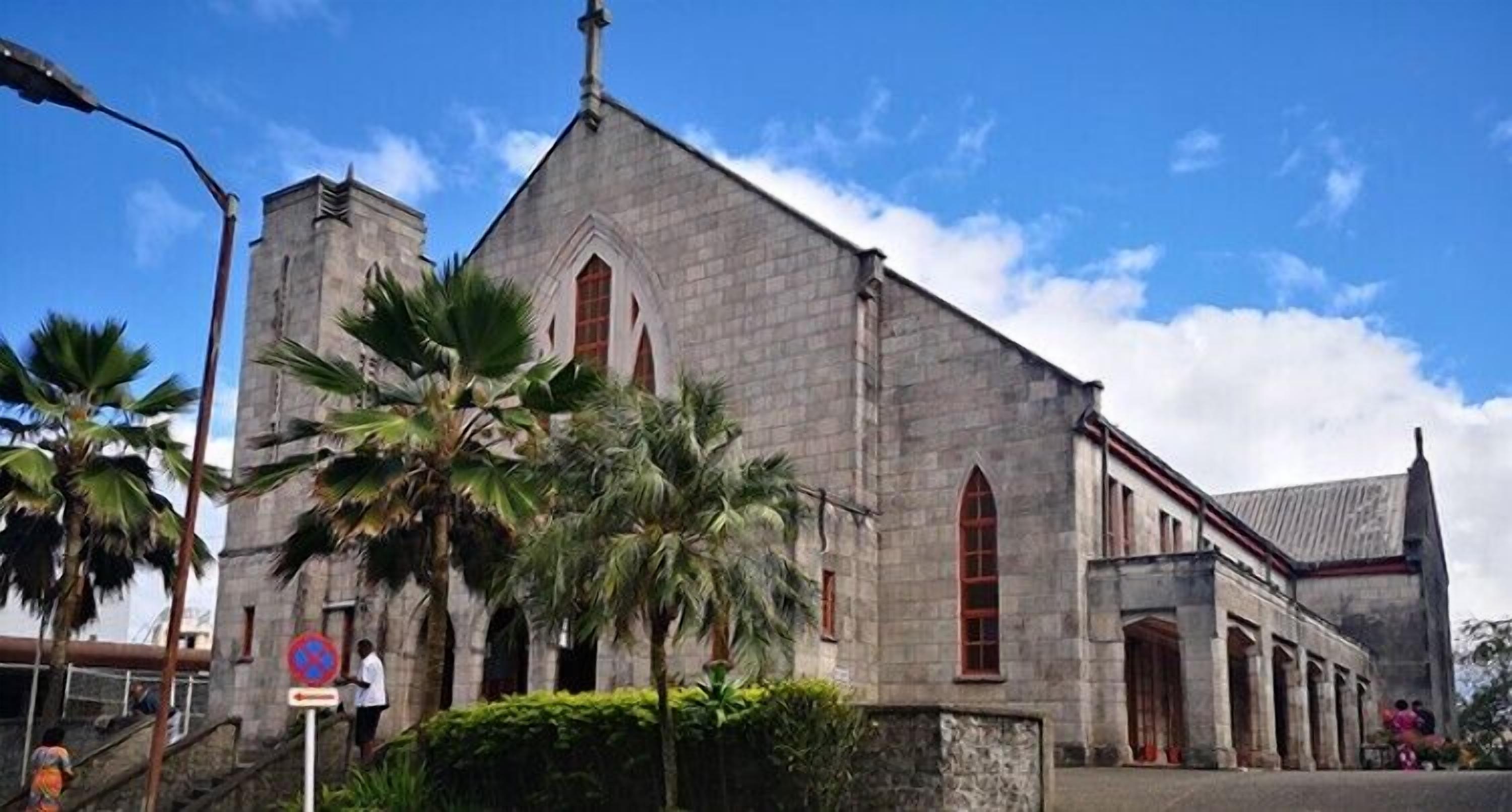A church with a tall steeple, arched windows, and a stone facade.