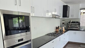 A modern kitchen with white cabinetry, stainless steel appliances, and a black countertop. - Island Accommodation Suva Premier Hospitality (Suva)