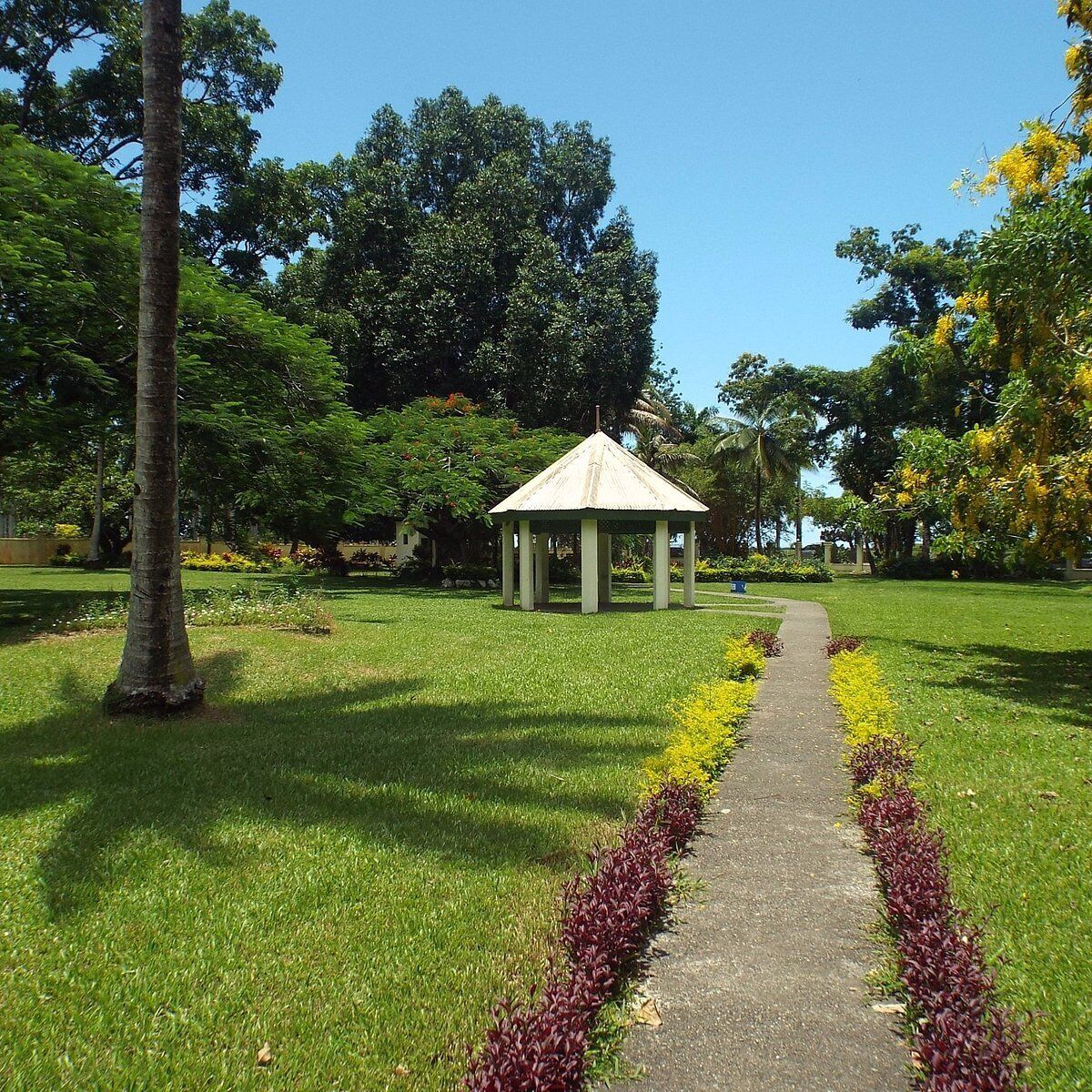 A gazebo in a park with a paved path leading to it.