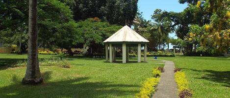 A gazebo in a park with a paved path leading to it.