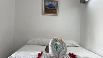 Una habitación de hotel con una cama bien tendida, un cuadro enmarcado en la pared y una lámpara.