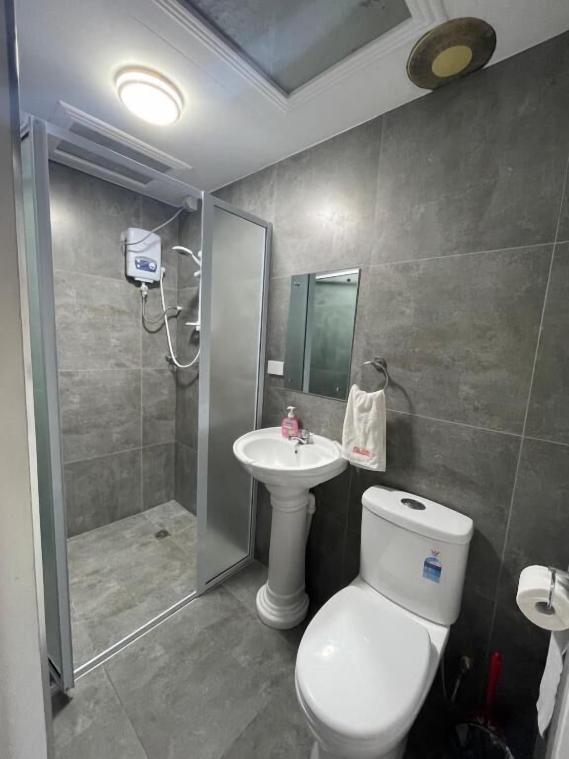 Une salle de bain avec une douche, un lavabo sur colonne et des toilettes.