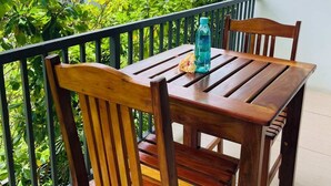 A wooden table and chairs on a balcony with a view of a house and greenery. - Island Accommodation Suva Premier Hospitality (Suva)