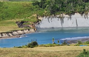 A coastal landscape with a cliff, beach, and vegetation. - Peace and Tranquility ... farmland, river and west coast beach - perfection! (Mimi)