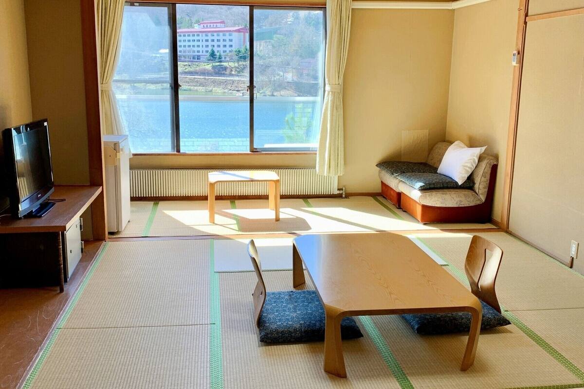 A room with tatami mats, a television, a sofa, and a table.