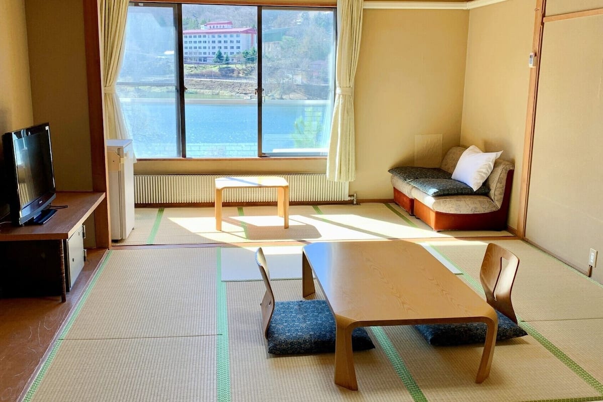 A room with tatami mats, a television, a sofa, and a table.