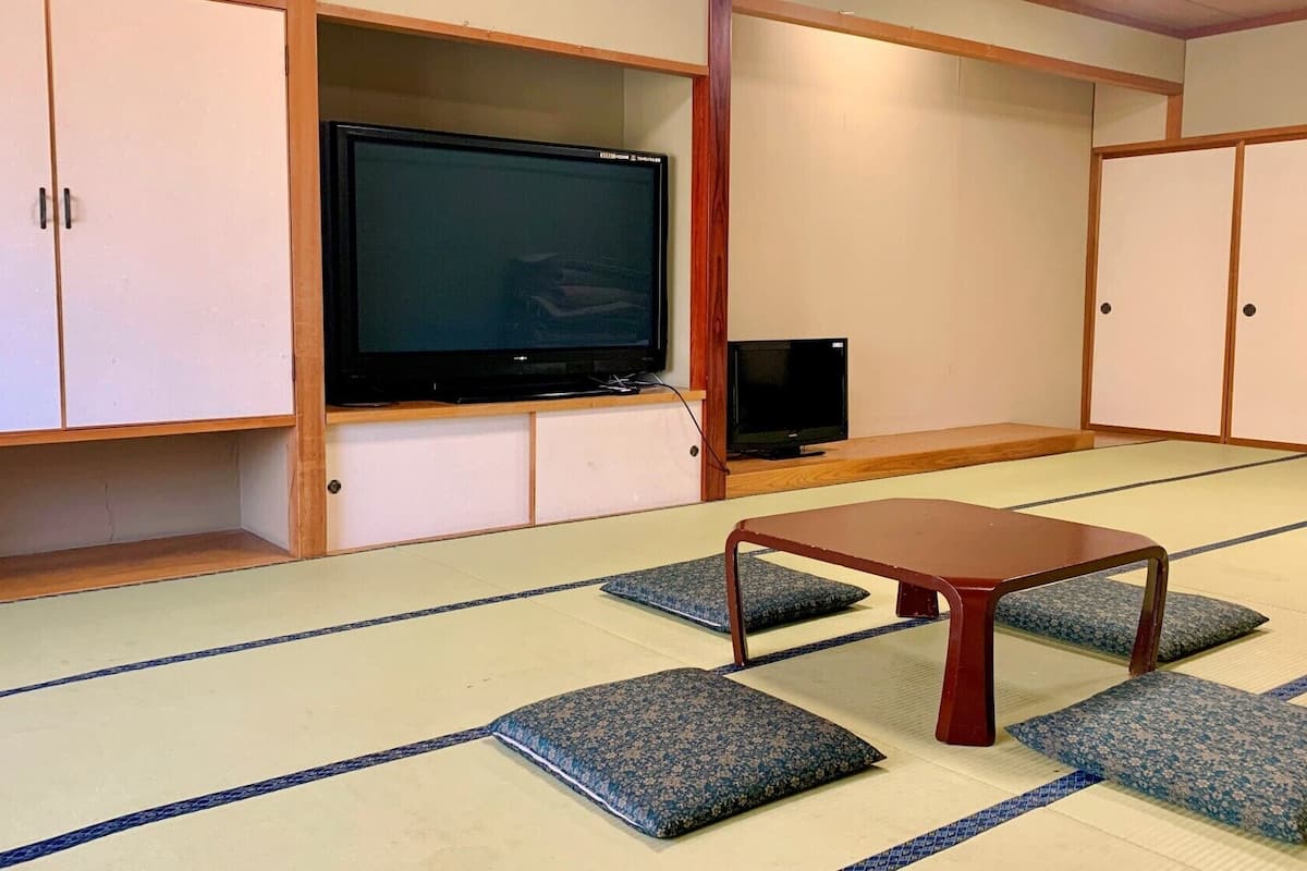 A traditional Japanese room with tatami flooring, a television, and a small table.