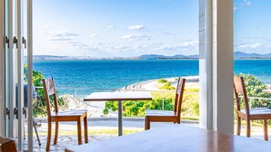 A patio with a table and chairs overlooking a beach and the sea. - 413 Hamahiga Hotel&cafe (Uruma)