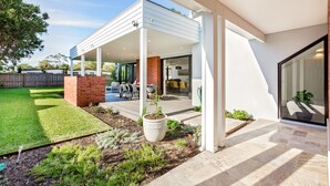 A modern house with a covered patio, a brick fireplace, and a well-maintained lawn. - Chesters by the Bay: luxury family home, walk to beach and town (Dunsborough)