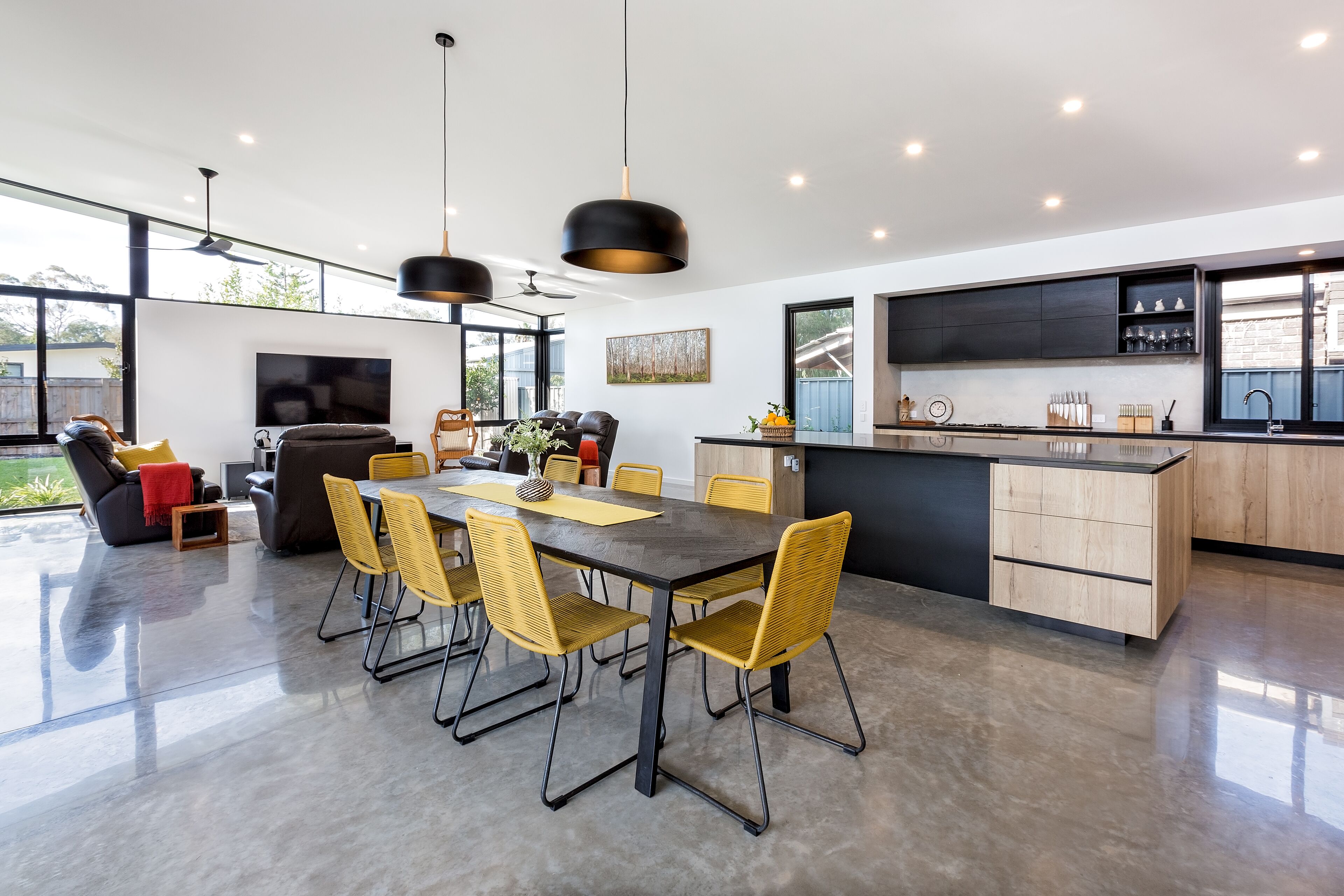 Een moderne keuken met een centraal eiland, een eethoek met stoelen en een groot raam.