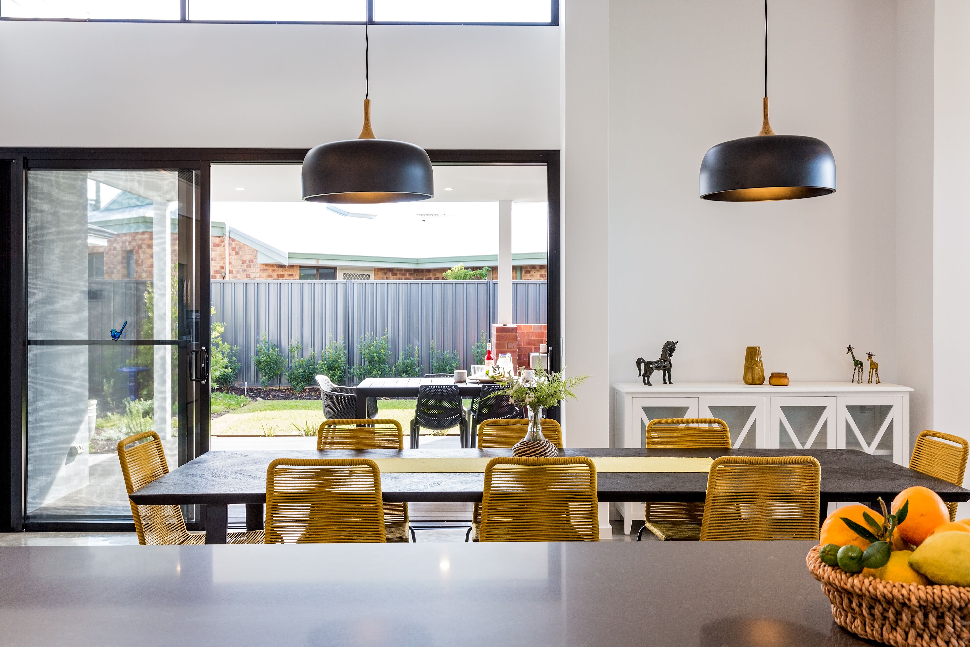 Un espace repas comprenant une grande table, des chaises et des luminaires suspendus.
