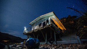 Une cabane rustique avec un toit en pente, une petite véranda et une seule source de lumière.