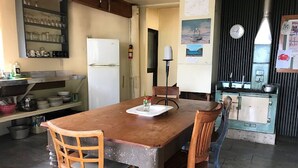 Une cuisine avec une table en bois, des chaises, un réfrigérateur et une cuisinière.