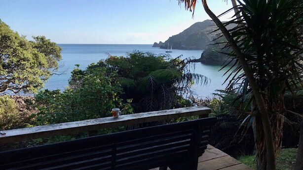 Un banc en bois, placé en surplomb d’une zone côtière, d’où l’on peut admirer la mer et une île lointaine.