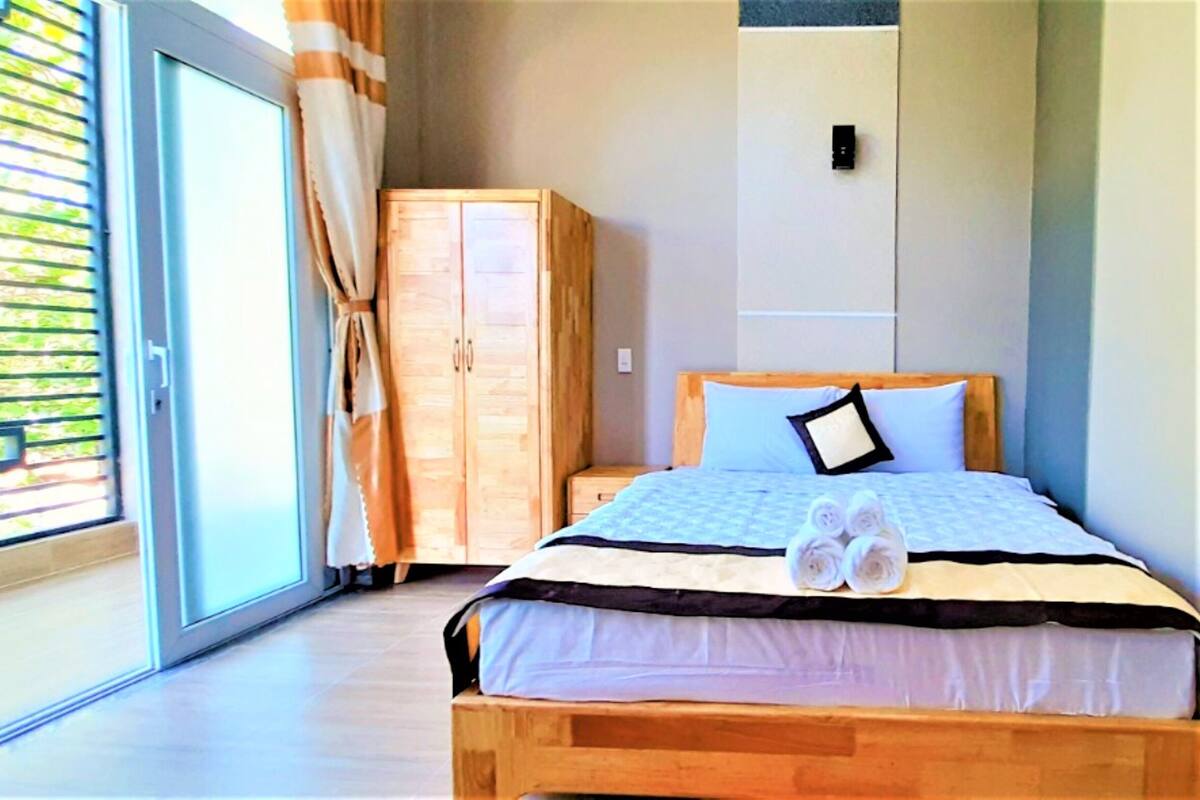 A bedroom with a wooden bed, a wardrobe, and a sliding glass door to a balcony.