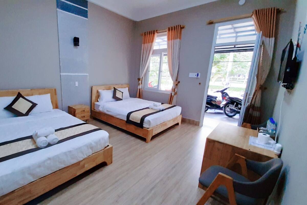 A hotel room with two wooden beds, a desk, and a chair.